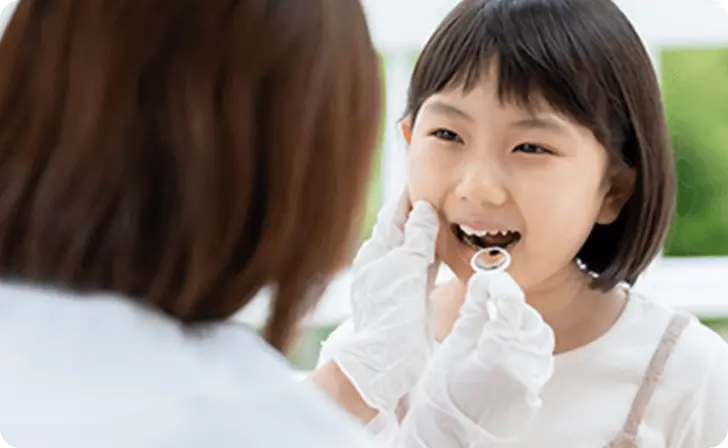 歯科医が優しく女の子の歯を診ている画像