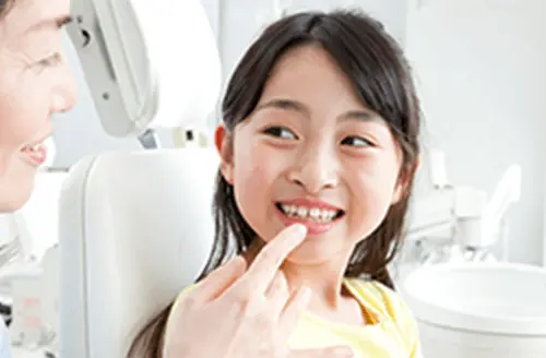 笑顔で女性歯科医と会話する女の子の画像
