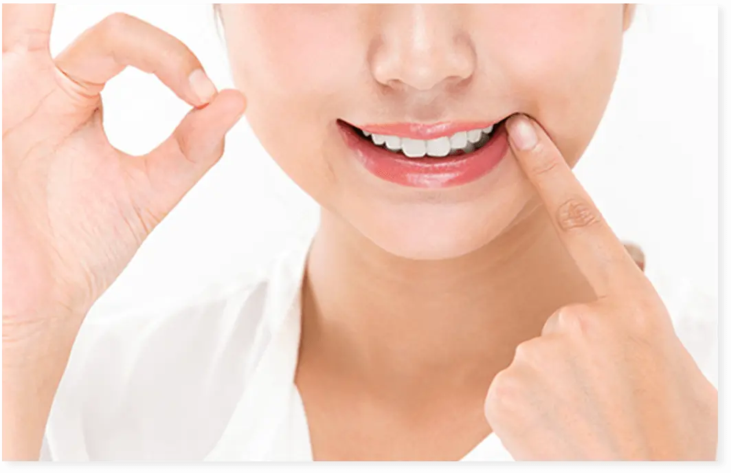 女性が笑顔で白い歯を見せてOKポーズしている画像