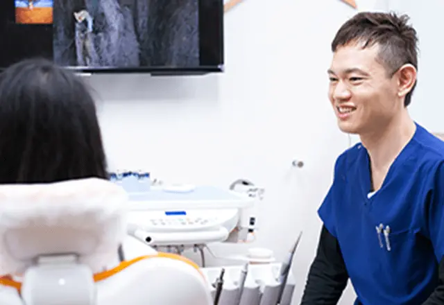 患者さんと治療相談をする男性歯科医の画像